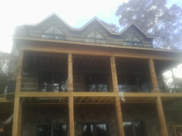 Dormers and porch framing on a large log home under construction — Roof Coating work by our crew in Fairfax